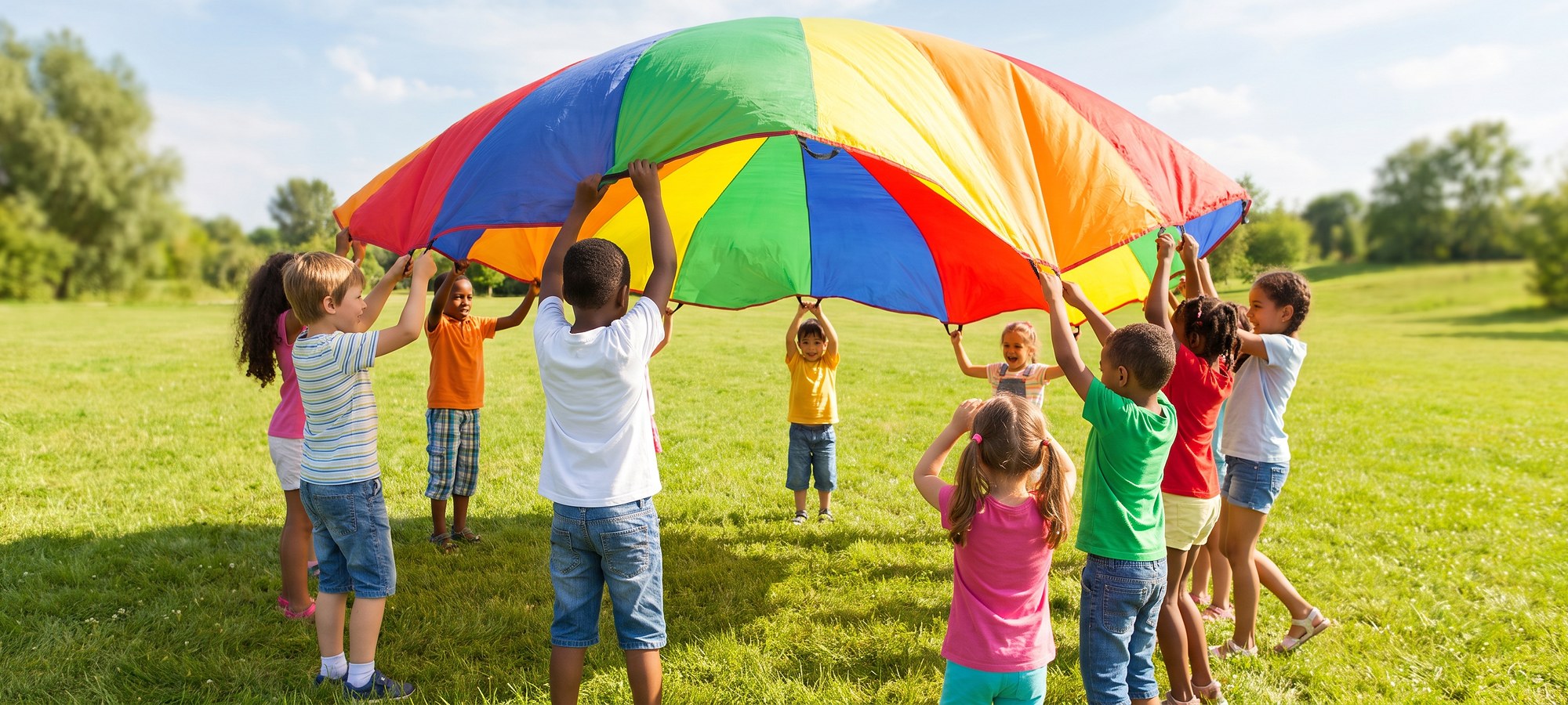 Children playing together under a colorful parachute